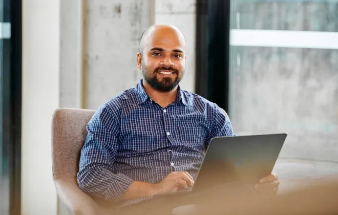Woman looking at camera with laptop on his lap
