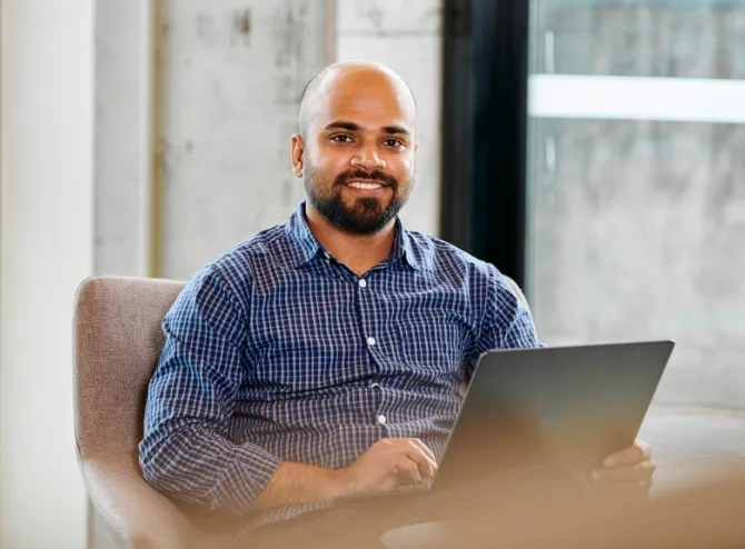 Woman looking at camera with laptop on his lap